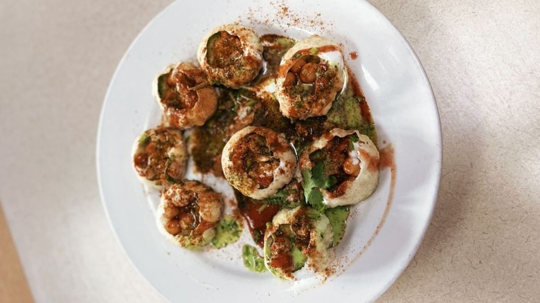 Overhead shot of gol gappay on plate filled with various chutneys and chickpeas