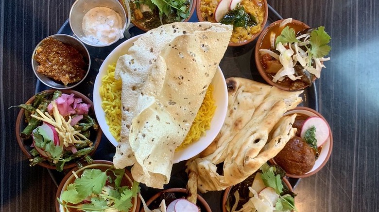Overhead shot of vegetarian thali for two people laden with over a dozen items