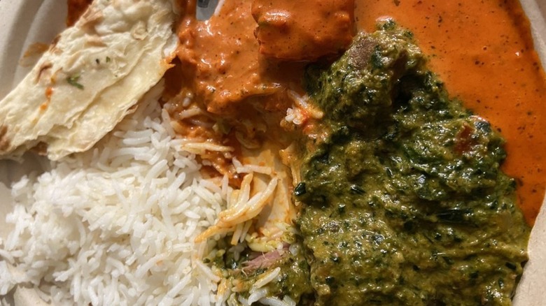 Plate topped with rice, naan, tikka masala, and lamb saagwala