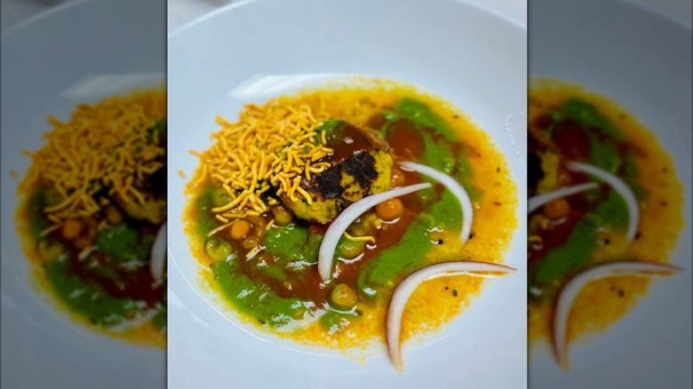 Chaat dish layered with sev, two chutneys, chickpeas, and raw onions
