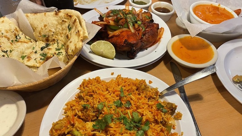 Table laden with biryani, naan, chicken tikka masala, butter chicken, and tandoori chicken