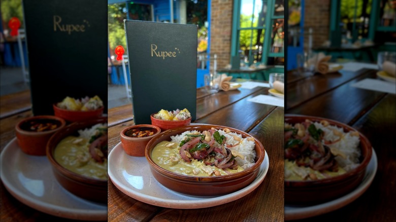 Indian stew on white plate with Rupee menu on wooden table