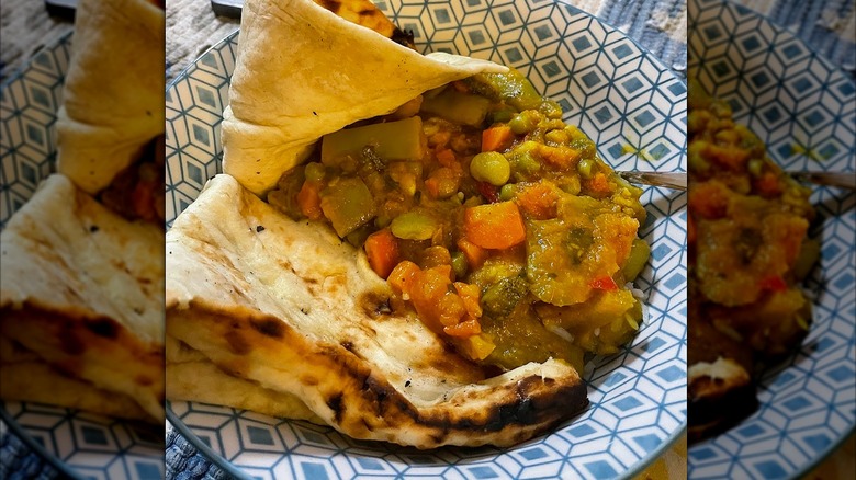 Veggie curry with naan in a blue and white bowl