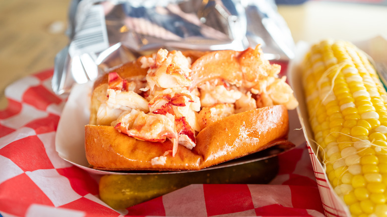 Lobster roll next to a corn of cob