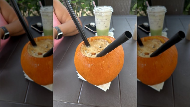 Iced pumpkin spice latte in real pumpkin with two straws