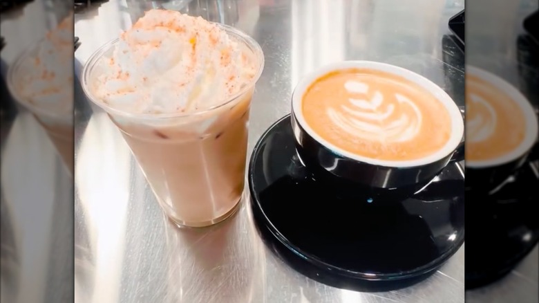 Iced and hot version of pumpkin pie latte beside one another on countertop