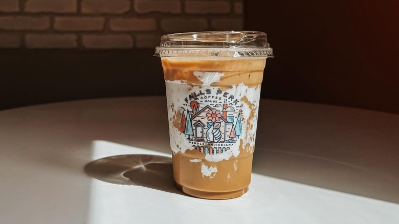 Iced pumpkin fluff latte in plastic to-go cup on sunlit table