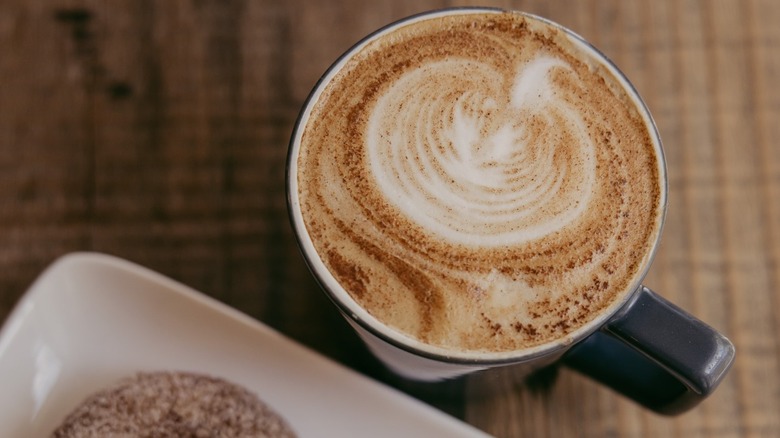 Overhead shot of richly spiced pumpkin spice latte with pumpkin latte art in mug