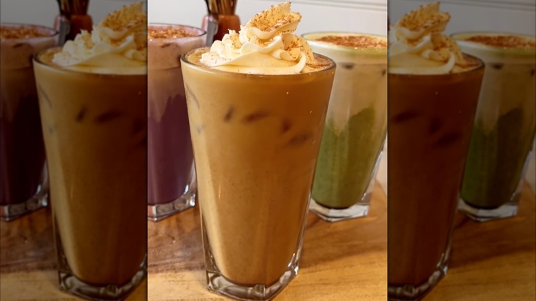 Pumpkin horchata latte in glass topped with whipped cream, alongside two other seasonal beverages