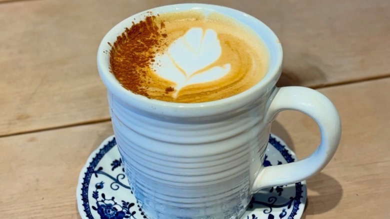 Pumpkin pie latte dusted with cinnamon in mug on saucer