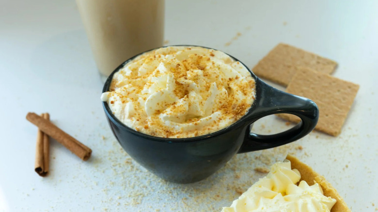 The Pumpkin Queen in mug alongside graham crackers and cinnamon sticks