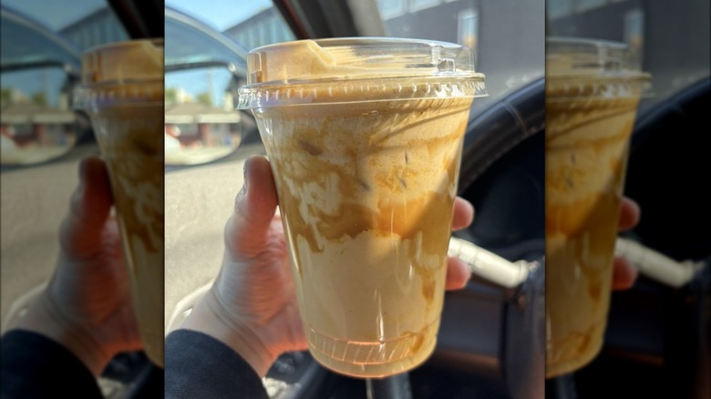 Hand holding iced Not Yo Mama's Pumpkin Spice Latte in car