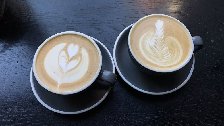 Two pumpkin stuff lattes in mugs on saucers