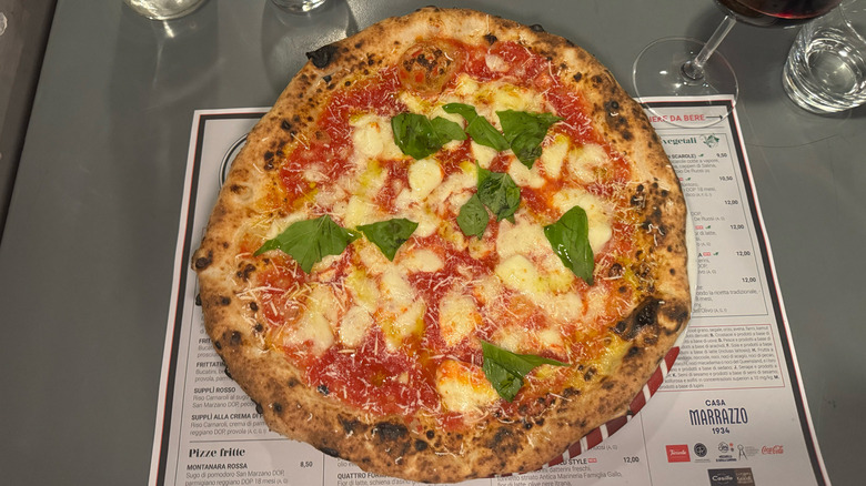 Margherita pizza from 50 Kalò in Naples, Italy on metal table with placemat menu