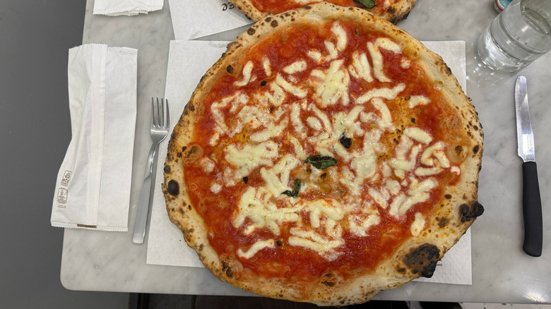 Margherita pizza from L'antica pizzeria da Michele in Naples, Italy, on marble table with placemat