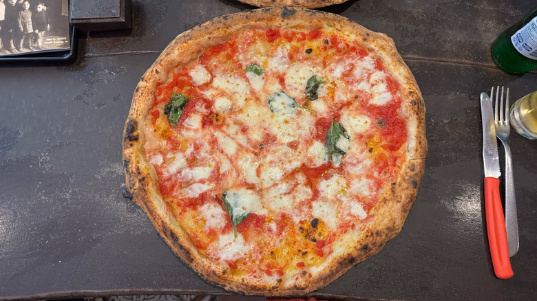 Margherita pizza from Sorbillo in Naples, Italy, on dark wood table