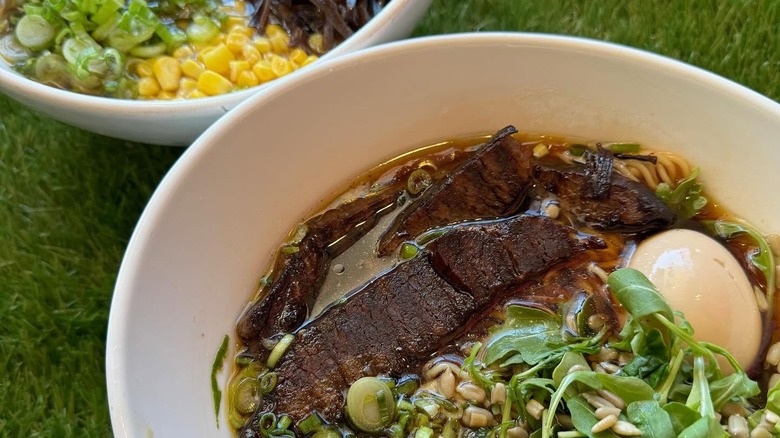 Two bowls of ramen placed on green grass