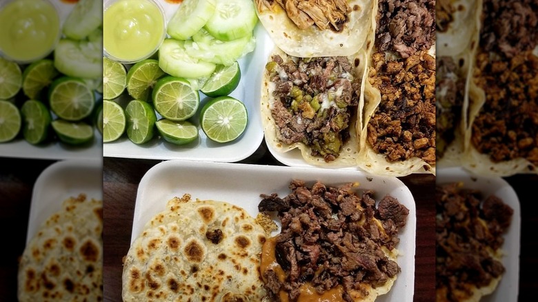 Several styrofoam plates with tacos, limes, cucumber slices
