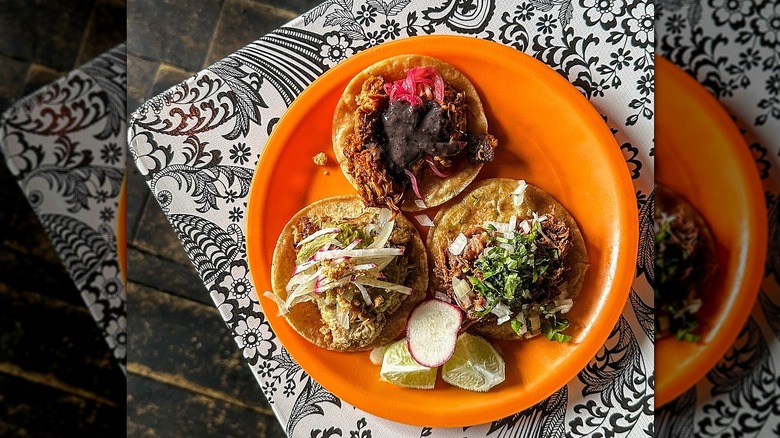 Top-down shot of three street tacos on orange plate