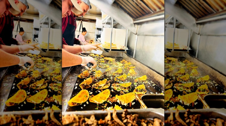 Lots of street tacos cooking on a flat top