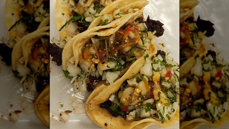 Close-up of three fully loaded soft tacos with doubled tortilla
