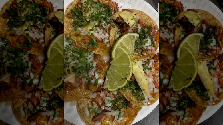 Overhead shot of five soft tacos on a paper plate with lime slices