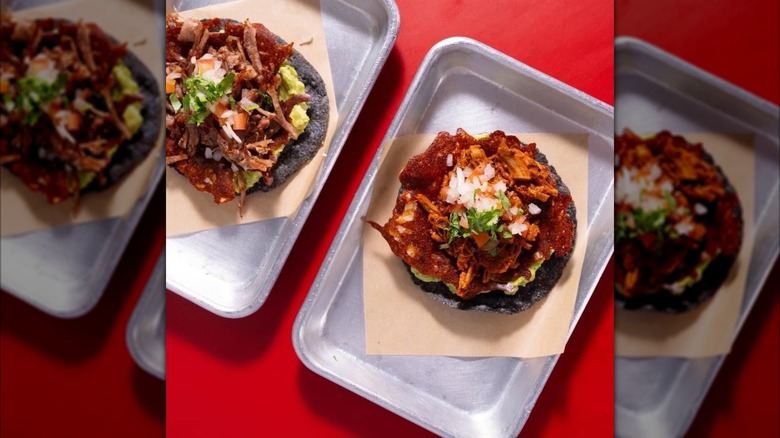 Two tacos in steel pans on red table