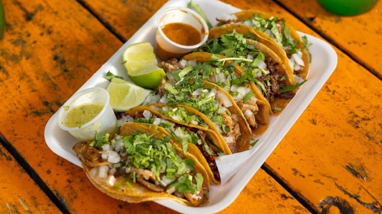 Row of tacos topped with herbs and salsa