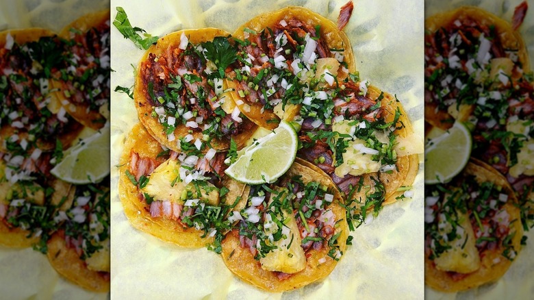 Several al pastor tacos displayed in a circle