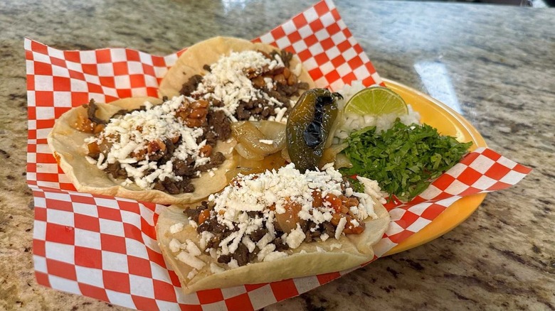 Three charros tacos with herbs and a lime