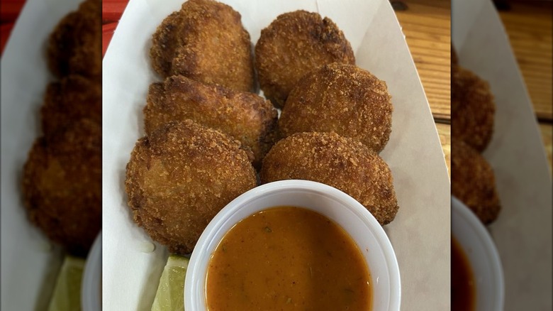Six crab cakes on plate with dipping sauce