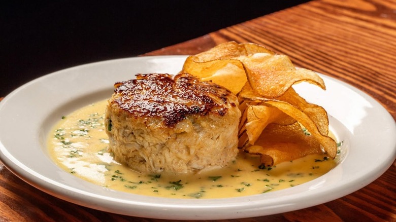 Crab cake on plate with sauce and potato chips
