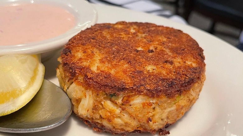 Crab cake with lemon and bowl of pink sauce