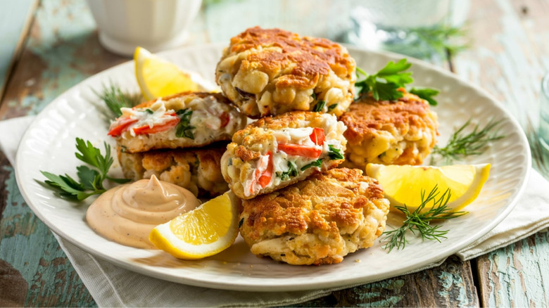 Crab cakes on plate with lemon wedges and sauce