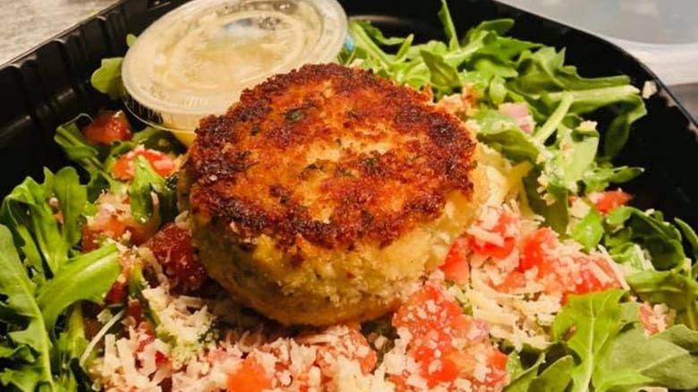 Crab cake on salad with dressing cup