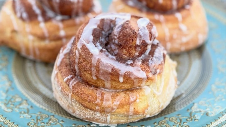 Three lightly glazed cinnamon rolls on ornate plate