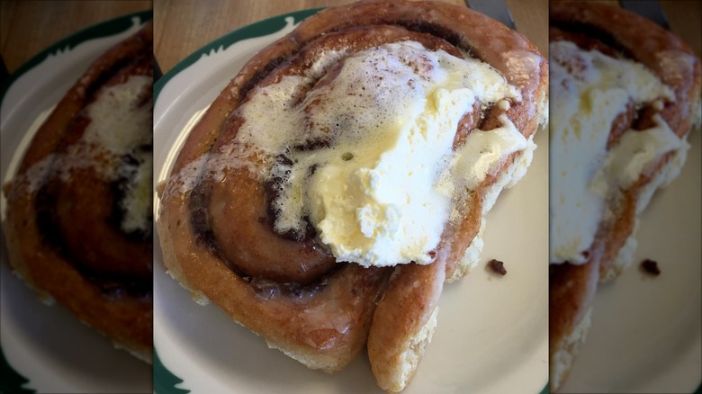 Overhead shot of cinnamon roll on plate with frosting melting on top