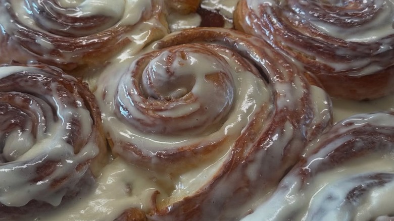 Several glazed cinnamon rolls on baking tray