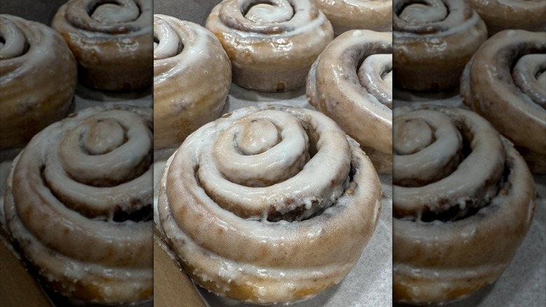 Five glazed cinnamon rolls on parchment paper