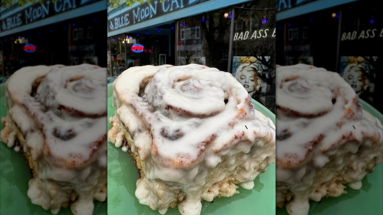Glazed cinnamon roll on plate in front of Blue Moon Cafe