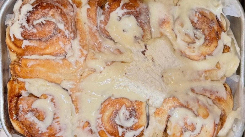 Cinnamon rolls slathered in icing in rectangular baking dish