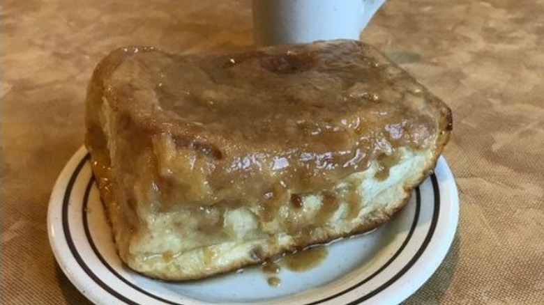 Caramel roll on plate in front of coffee cup