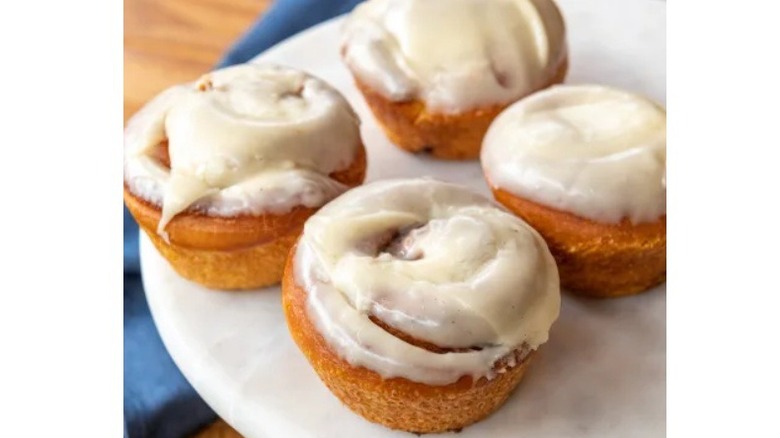 Four frosted cinnamon rolls on plate