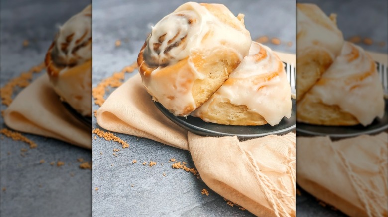 Two glazed cinnamon rolls on plate with napkin underneath