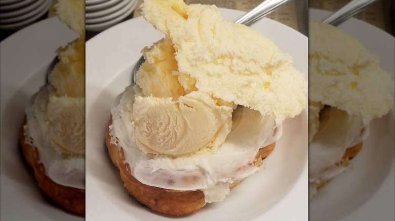 Cinnamon roll topped with ice cream on plate