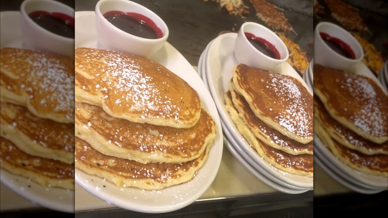 Two white plates of Orange Raspberry Pancakes at Goldy's Breakfast Bistro