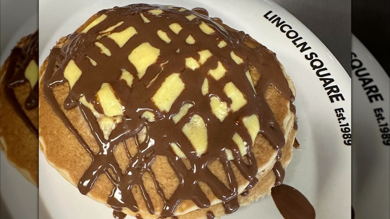 Pancakes with chocolate drizzle and cream sauce on Lincoln Square white plate