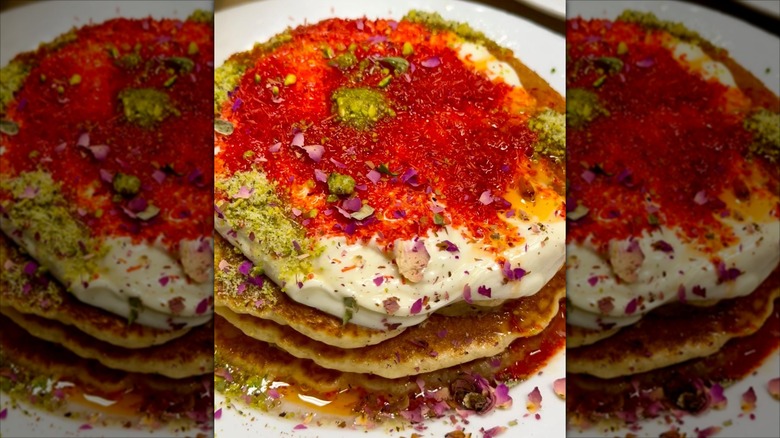 Decadent pancakes with red topping on white plate