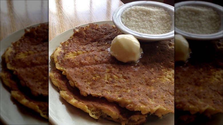 Two pancakes with butter on white plate