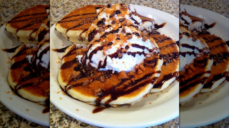 Pancakes with chocolate drizzle, whipped cream, and crumble on white plate